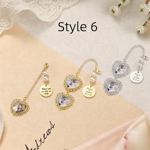 May include: Three heart-shaped photo charms with gold and silver metal frames. Each charm features a chain, two small white pearls, and a round metal tag engraved with text. The charms display miniature wedding photos inside the heart frames.