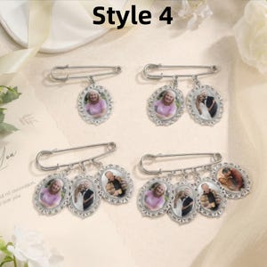 May include: Four silver-toned safety pins featuring oval-shaped photo charms. The pins display varying numbers of dangling frames, each containing a small color photograph of individuals or couples. The frames have a decorative, scalloped edge.