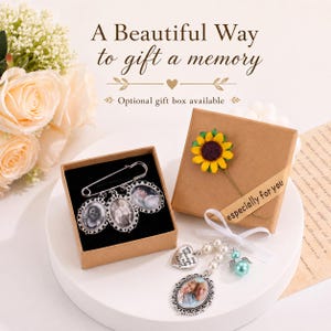 May include: A silver-toned safety pin brooch featuring three oval photo charms with ornate frames, alongside a separate charm set with a heart-shaped pendant, white pearls, a teal bead, and an oval photo charm, presented in brown gift boxes.