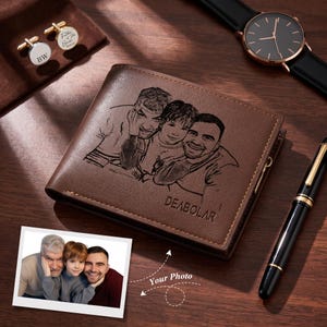 May include: A brown leather bifold wallet featuring a laser-engraved portrait of three people and the brand name DEABOLAR. The wallet is displayed alongside a black wristwatch, a black fountain pen, and two silver-toned circular cufflinks.