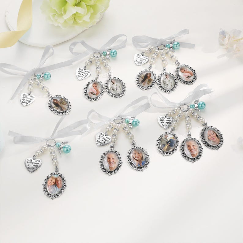 May include: A collection of six memorial photo charms featuring oval silver-toned frames, white faux pearl beads, and light blue accent beads. Each charm includes a white ribbon bow and a heart-shaped metal tag engraved with the text You are always in my heart.