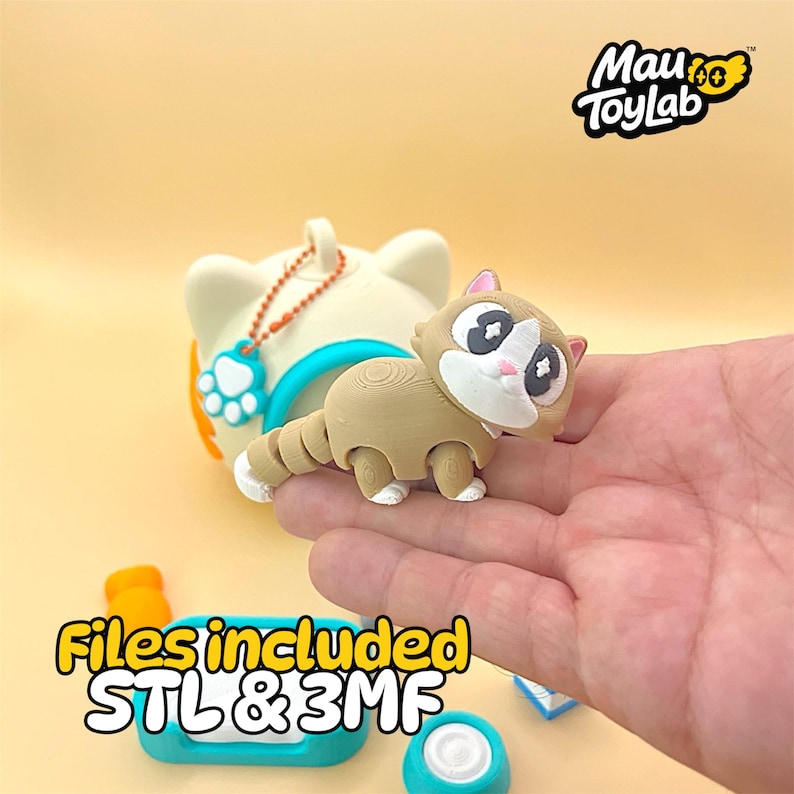 May include: A tan and white 3D printed cat figurine with large dark eyes and a segmented tail, positioned in front of a cream-colored cat-shaped container with a teal rim and a paw print charm. The text Mau ToyLab and Files included STL & 3MF appear.