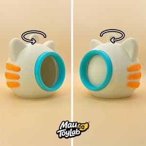 May include: A spherical off-white cat-shaped toy with three orange stripes on each side, a bright blue circular opening, and a small loop on top. A black arrow indicates rotation. The text Mau ToyLab is printed at the bottom of the image.