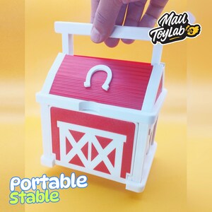 May include: A red and white portable stable toy with a handle. The stable features a red roof with a white horseshoe and a red barn door with white accents. The words "Portable Stable" are printed on the front.