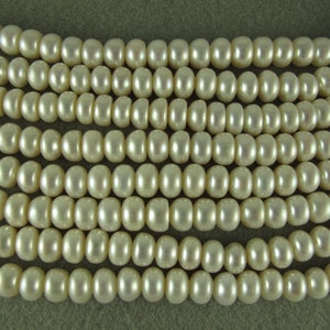 May include: A strand of off-white round pearls. The pearls are smooth and have a slight sheen.
