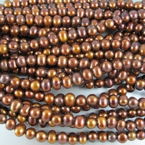 May include: Strands of brown freshwater pearls. The pearls have a lustrous, oval shape and vary in shades from light gold to deep chocolate. The pearls are strung together, creating a beautiful, natural jewelry component.