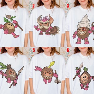 Puede incluir: Camisetas blancas con ilustraciones de dibujos animados de personajes tribales o fant&aacute;sticos. Cada dise&ntilde;o presenta una criatura &uacute;nica con varios colores y accesorios, como lanzas, garrotes y tocados. Las ilustraciones son de estilo caricaturesco.
