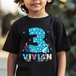 May include: Black t-shirt featuring a large blue number 3 filled with snowflakes, with the name "VIVIAN" below. The shirt has images of animated characters. The design is centered on the front of the shirt.