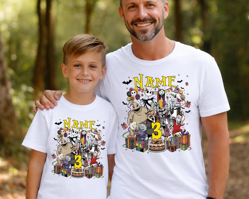 Pode incluir: Duas camisetas brancas com um gr&aacute;fico colorido de personagens de The Nightmare Before Christmas. As camisas t&ecirc;m a palavra "NAME" acima do gr&aacute;fico e o n&uacute;mero "3" no design. As camisas s&atilde;o usadas por um pai e seu filho.