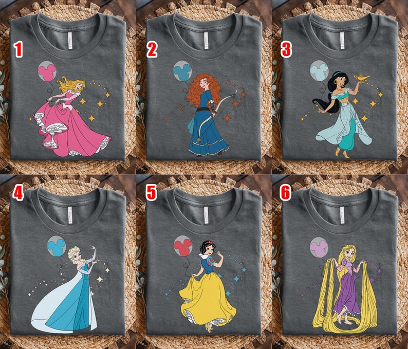 May include: Six charcoal gray t-shirts with different cartoon princess designs. Each shirt features a princess in a colorful dress with a matching balloon and sparkling accents. The princesses include Aurora, Merida, Jasmine, Elsa, Snow White, and Rapunzel.