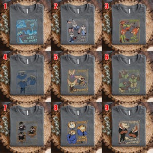 May include: Gray t-shirts featuring characters from Zootopia 2. Each shirt displays a different character or character group, including Judy Hopps, Nick Wilde, and Flash, with their names printed below. The shirts are displayed on a woven surface.