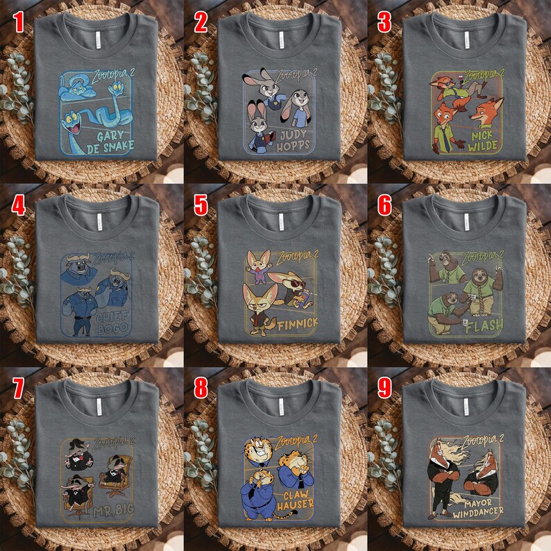 May include: Gray t-shirts featuring characters from Zootopia 2. Each shirt displays a different character or character group, including Judy Hopps, Nick Wilde, and Flash, with their names printed below. The shirts are displayed on a woven surface.