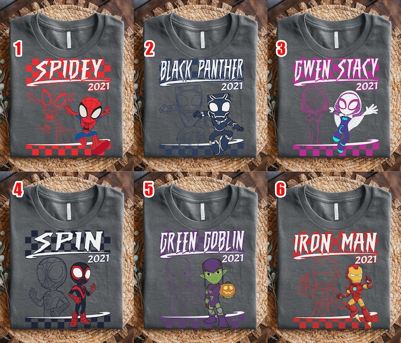 May include: Six grey t-shirts with superhero designs. Each shirt features a different character: Spidey, Black Panther, Gwen Stacy, Spin, Green Goblin, and Iron Man. Each design includes the year 2021.