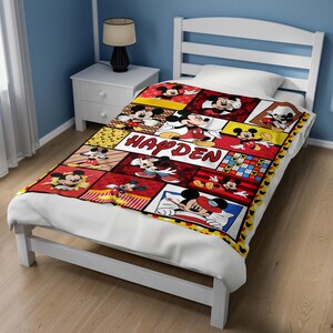 Pu&ograve; includere: Una colorata coperta a tema Topolino con una struttura del letto bianca. La coperta presenta varie immagini di Topolino in un design patchwork con il nome "HAYDEN" al centro. La coperta &egrave; rossa, gialla e nera.