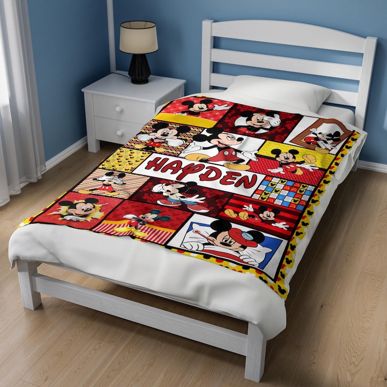 Pu&ograve; includere: Una colorata coperta a tema Topolino con una struttura del letto bianca. La coperta presenta varie immagini di Topolino in un design patchwork con il nome "HAYDEN" al centro. La coperta &egrave; rossa, gialla e nera.