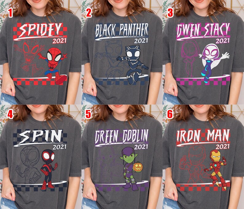 May include: Six charcoal grey t-shirts featuring Marvel characters. Each shirt has a character name and "2021" printed on it. Characters include Spidey, Black Panther, Gwen Stacy, Spin, Green Goblin, and Iron Man.