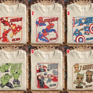 K&ouml;nnte beinhalten: Sechs beige T-Shirts mit Marvel-Superhelden-Grafiken. Jedes Shirt zeigt einen anderen Charakter: Iron Man, Spider-Man, Captain America, Hulk, Thor und Groot. Die Shirts haben den Namen der Figur und das Gr&uuml;ndungsjahr.