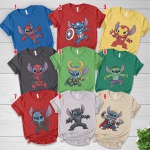 May include: A collection of nine short-sleeved t-shirts in various colors, each featuring a cartoon character in a superhero costume. The shirts are blue, red, yellow, gray, green, and tan. The designs include Spider-Man, Captain America, Iron Man, Deadpool, Loki, Hulk, Black Widow, Black Panther, and Thor.