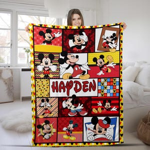 Pu&ograve; includere: Una coperta personalizzata con un collage di immagini di Topolino in varie pose. La coperta ha un bordo giallo con sagome di Topolino e il nome "HAYDEN" a grandi lettere rosse. Lo sfondo include pannelli rossi, bianchi e neri.