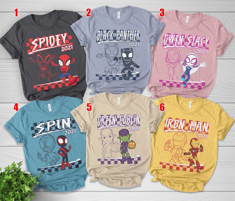 May include: Six t-shirts with Marvel character designs. Each shirt has a character's name and the year 2021, plus a cartoon image. The shirts are in various colours: grey, blue, pink, light blue, beige, and yellow.