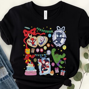 May include: A black t-shirt featuring a colorful graphic print of various superheroes, including Spider-Man, Iron Man, and Hulk. The design includes a birthday cake, gift boxes, balloons, and the text "NAME" and "5" surrounded by decorative elements.