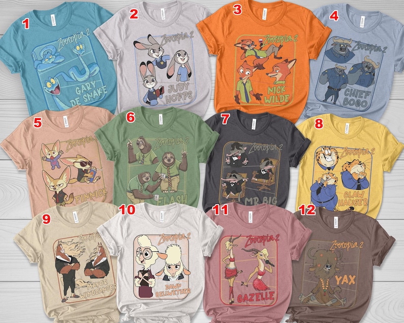 May include: A collection of twelve Zootopia 2 graphic t-shirts in various colors. Each shirt features a different character or group of characters from the animated movie, with text labels such as "Gary De Snake", "Judy Hopps", and "Nick Wilde".