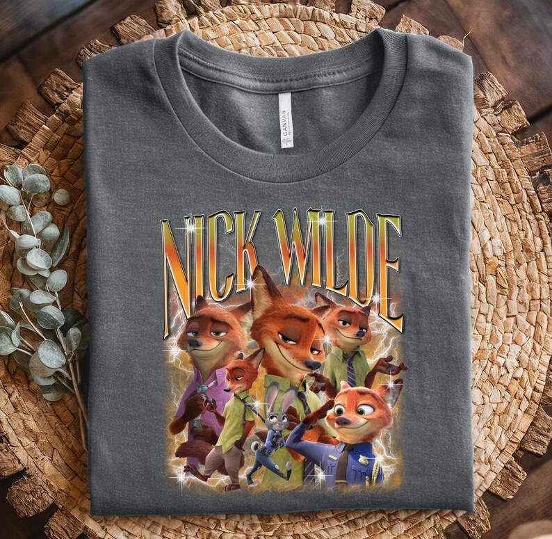 May include: Dark gray t-shirt featuring a graphic of Nick Wilde from Zootopia. The design includes multiple images of the fox character with the text "NICK WILDE" in a yellow and orange gradient font with lightning bolt accents.