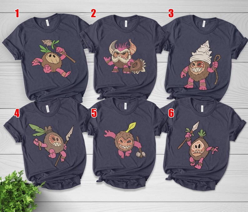 Puede incluir: Seis camisetas azul marino con gr&aacute;ficos de monstruos de dibujos animados. Cada camiseta presenta un dise&ntilde;o de monstruo diferente en tonos de marr&oacute;n, rosa y verde. Los monstruos sostienen varios objetos como lanzas y palos.