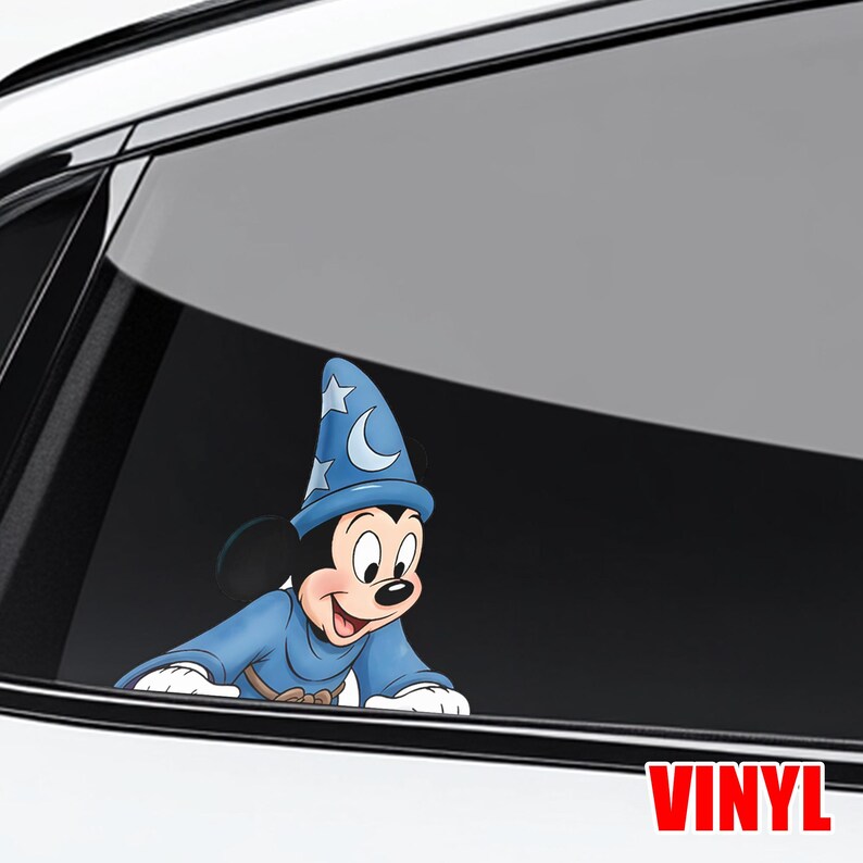 Puede incluir: Una calcoman&iacute;a de vinilo de Mickey Mouse con un disfraz de mago azul, con una luna creciente y estrellas en su sombrero. La calcoman&iacute;a est&aacute; aplicada a la ventana de un coche. La palabra "VINYL" est&aacute; impresa en rojo.