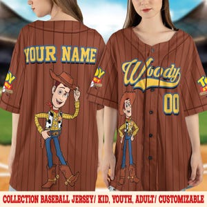 Puede incluir: Camiseta de b&eacute;isbol marr&oacute;n con rayas finas, con un personaje de dibujos animados de vaquero. La camiseta tiene el nombre "Woody" y el n&uacute;mero "00" en la parte delantera. La parte trasera de la camiseta dice "YOUR NAME". El texto "COLLECTION BASEBALL JERSEY/ KID, YOUTH, ADULT/ CUSTOMIZABLE" est&aacute; en la parte inferior.