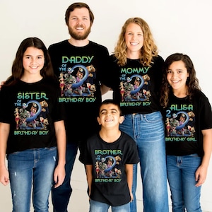 May include: A family wearing matching black t-shirts with a birthday theme. The shirts have text that says "Daddy", "Mommy", "Sister", "Brother", and "Alisa" with "Birthday Boy" or "Birthday Girl" below. Each shirt features a colorful graphic with the number "2".