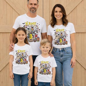 Pode incluir: Quatro pessoas vestindo camisetas brancas com um design gr&aacute;fico colorido com personagens e o n&uacute;mero 3. As camisas tamb&eacute;m t&ecirc;m a palavra "NAME" impressa. A fam&iacute;lia est&aacute; em frente a uma porta de madeira.