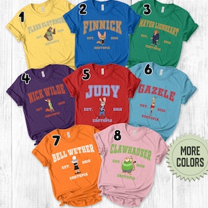 May include: A collection of eight colorful t-shirts, each featuring a different character from Zootopia. The shirts are in various colors, including yellow, blue, green, purple, red, light blue, orange, and pink. Each shirt has a character's name and the word "Zootopia" printed on it.