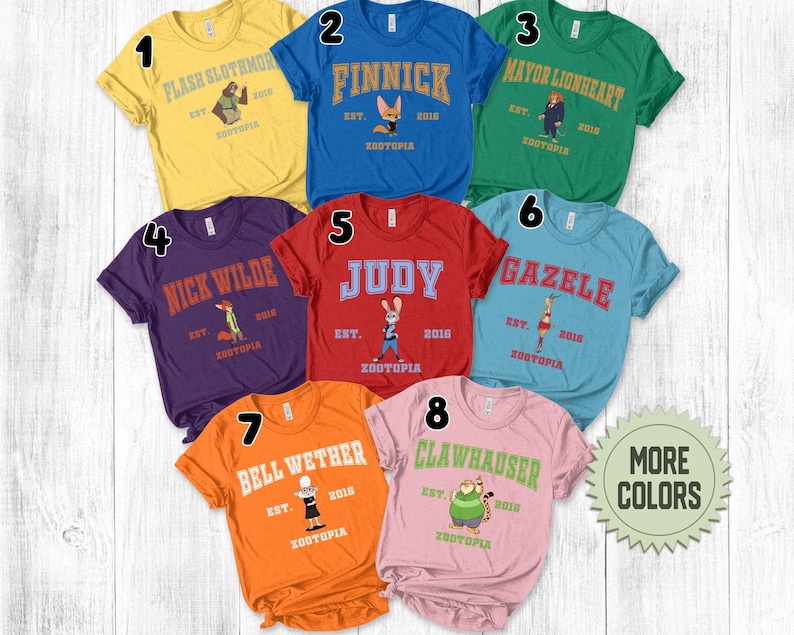May include: A collection of eight colorful t-shirts, each featuring a different character from Zootopia. The shirts are in various colors, including yellow, blue, green, purple, red, light blue, orange, and pink. Each shirt has a character's name and the word "Zootopia" printed on it.