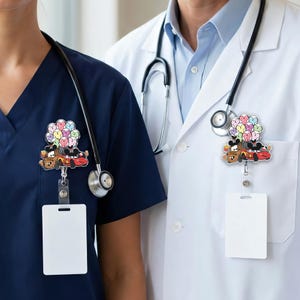 Op de afbeelding: Twee medische professionals dragen badge reels met cartoon thema. De reels tonen cartoon auto's en een cluster van hartvormige ballonnen in verschillende kleuren. De badge reels zijn bevestigd aan witte ID-badges.