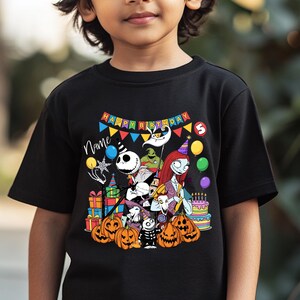 May include: Black t-shirt featuring a colorful graphic of characters from The Nightmare Before Christmas, pumpkins, gifts, and a birthday cake. The text "Happy Birthday" is displayed above the characters. The number "5" is also visible.