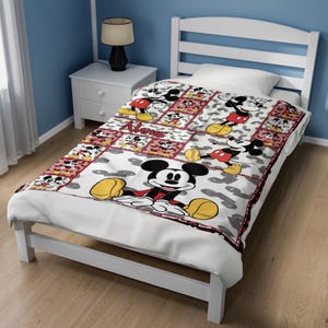 May include: A white bed with a Mickey Mouse themed quilt. The quilt features a patchwork design with images of Mickey Mouse in various poses, set against a red and white background. The word "Name" is also visible on the quilt.