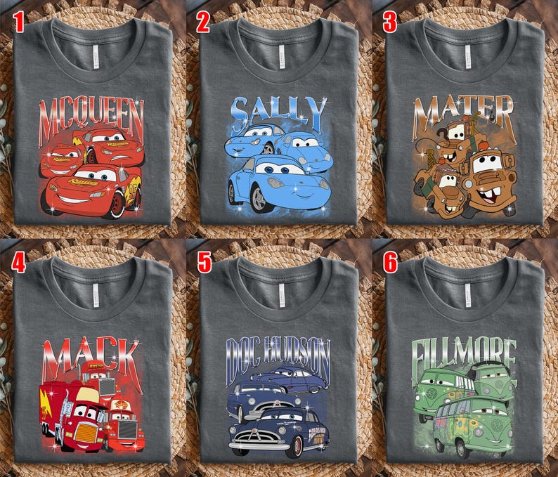 May include: Six gray t-shirts featuring characters from the animated movie "Cars." Each shirt displays a different character's name and image: McQueen, Sally, Mater, Mack, Doc Hudson, and Fillmore. The designs are in various colors.