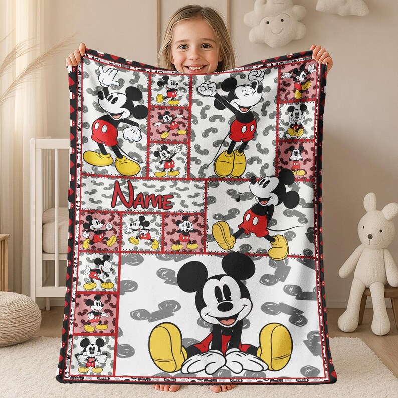 May include: A white blanket featuring a patchwork design with images of Mickey Mouse in various poses. The blanket has a red border and the word "Name" in red. The background has gray shapes.