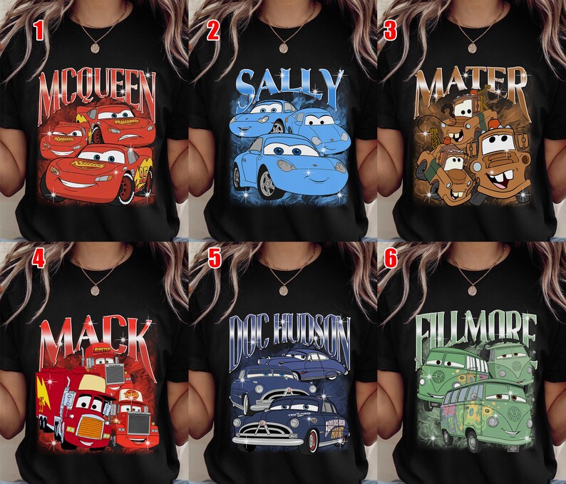 May include: Black t-shirts featuring characters from the animated movie "Cars." Designs include Lightning McQueen, Sally, Mater, Mack, Doc Hudson, and Fillmore. Each shirt has a different graphic and character name.