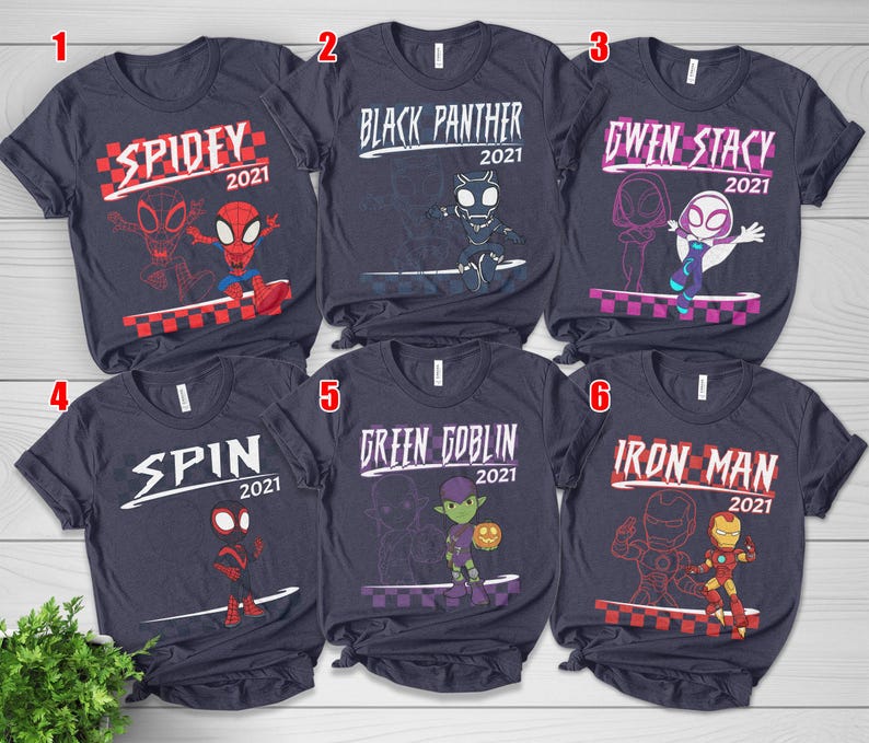 May include: Six navy blue t-shirts, each showcasing a different Marvel character. The shirts feature the character's name and the year 2021, accompanied by a graphic illustration. Characters include Spidey, Black Panther, Gwen Stacy, Spin, Green Goblin, and Iron Man.