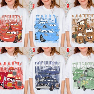 May include: White t-shirts featuring various Cars movie characters. Designs include Lightning McQueen, Sally, Mater, Mack, Doc Hudson, and Fillmore. Each design has a vintage, distressed look, with character names prominently displayed.