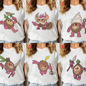 Puede incluir: Camisetas blancas con seis dise&ntilde;os diferentes de monstruos de dibujos animados. Cada monstruo tiene una apariencia &uacute;nica, con diferentes colores y accesorios. Los dise&ntilde;os incluyen criaturas con lanzas, garrotes y otras herramientas, todo en un estilo l&uacute;dico.