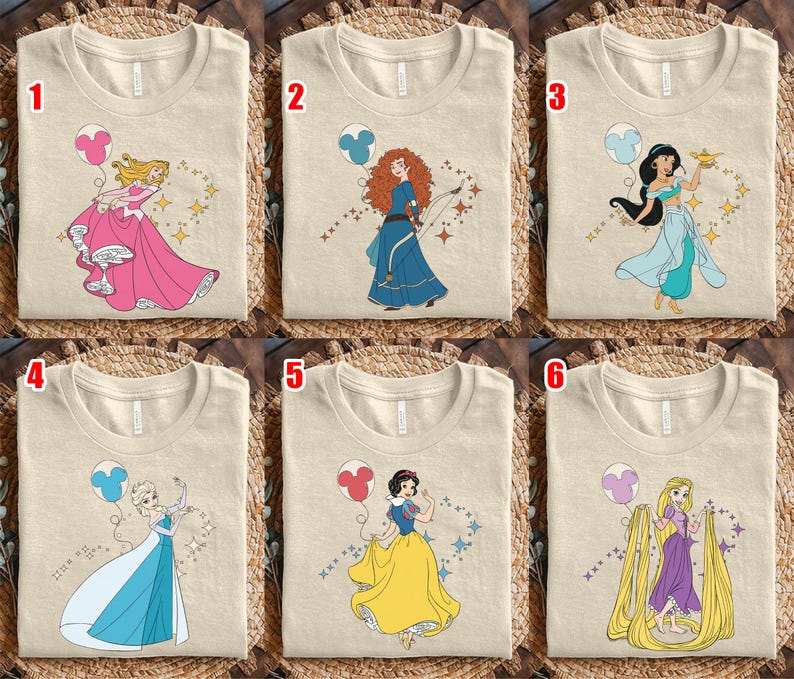 May include: Six beige t-shirts with different princess designs. Each shirt features a cartoon princess with a balloon and star accents. The princesses are in various poses and outfits, including pink, blue, and yellow dresses.