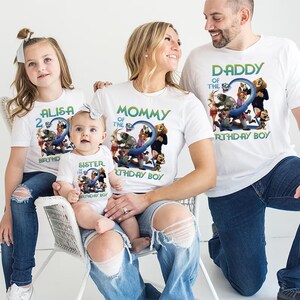 May include: White t-shirts with matching graphics and text for a family. The shirts feature a blue number 2 with cartoon characters and the phrases "ALISA 2 BIRTHDAY BOY", "MOMMY OF THE BIRTHDAY BOY", "SISTER OF THE BIRTHDAY BOY", and "DADDY OF THE BIRTHDAY BOY".