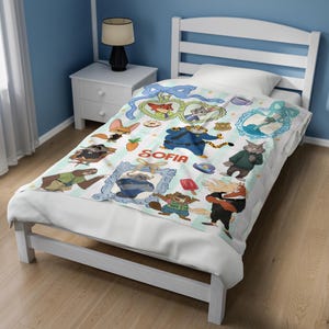 Puede incluir: Una colcha blanca con personajes de dibujos animados de Zootopia, con el nombre "SOFIA" en el centro. El dise&ntilde;o incluye varios personajes en marcos decorativos y elementos dispersos sobre un fondo a rayas.