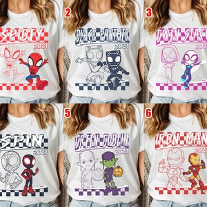 May include: White t-shirts with superhero graphics. Each shirt displays a different character or pair, with the year 2021. The designs include Spidey, Black Panther, Gwen Stacy, Spin, Green Goblin, and Iron Man.