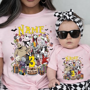 Pode incluir: Camisetas e body rosa combinando com um gr&aacute;fico colorido de personagens, presentes e um bolo. A palavra "NAME" est&aacute; acima do gr&aacute;fico, e o n&uacute;mero "3" &eacute; amarelo. O beb&ecirc; usa uma faixa xadrez em preto e branco e &oacute;culos de sol.