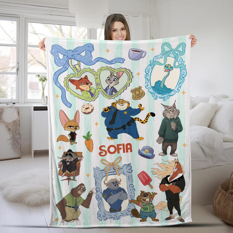 Puede incluir: Una manta a rayas blancas y verde claro con personajes de dibujos animados de Zootopia. La manta presenta ilustraciones de Nick Wilde, Judy Hopps y el Jefe Bogo. El nombre "SOFIA" est&aacute; impreso en rojo. La manta est&aacute; sostenida por una persona.