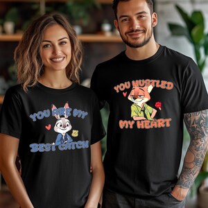 May include: Two black t-shirts featuring cartoon characters. The left shirt displays a rabbit with a badge and the text "YOU ARE MY BEST CATCH". The right shirt displays a fox holding a red popsicle with the text "YOU HUSTLED MY HEART".